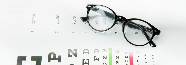 A pair of eyeglasses sitting atop an eye exam chart
